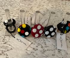 four different colored polka dots on black, white and red balls with name tags attached to them