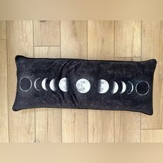 the phases of the moon are shown on this black pillow case, which is hung on a wood floor