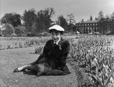 an old photo of a woman sitting in the grass