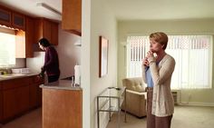 a man standing in a living room next to a kitchen and looking at another person