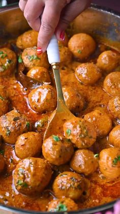 a person is spooning some meatballs out of a pan with sauce on it