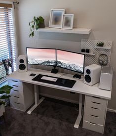 a computer desk with two monitors and speakers