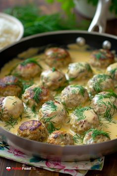 a pan filled with meatballs covered in gravy and garnished with dill