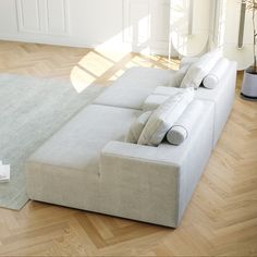 a white couch sitting on top of a hard wood floor next to a plant in a vase