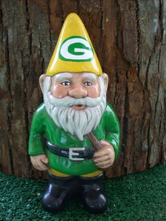 a green bay packers gnome figurine sitting next to a tree