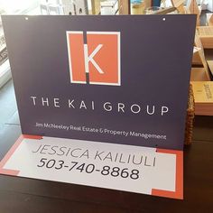 there is a sign that says the kaj group in front of bookshelves