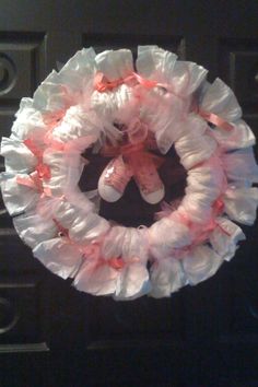 a baby's diaper wreath hanging on the front door to be used as a decoration