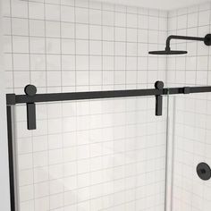 a white tiled bathroom with black handles and shower doors on the wall, along with tile flooring