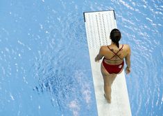 a woman in a red swimsuit standing on the edge of a swimming pool