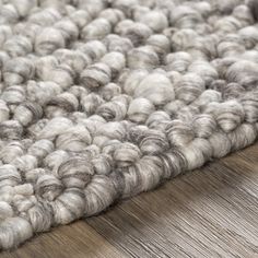 a close up view of a rug on the floor with wool and wood in the background