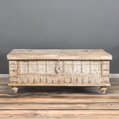 an old wooden box sitting on top of a hard wood floor next to a gray wall