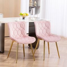 two pink chairs sitting next to each other on top of a hard wood floor