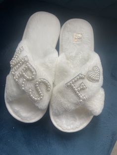 a pair of white slippers with the word bride written on one side and heart embellishments on the other