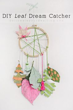 an image of a dream catcher made out of paper leaves and other things that are hanging on the wall