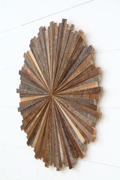 a wooden fan hanging on the side of a wall in front of a white wall