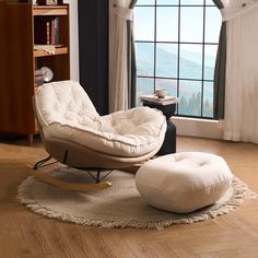 a white chair and ottoman in front of a window with a mountain view behind it