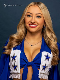 a woman wearing a blue and white cheerleader outfit smiling at the camera with her hands on her hips