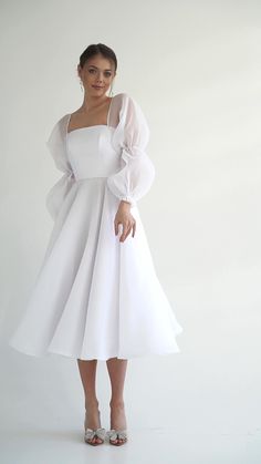 a woman in a white dress posing for the camera with her hands on her hips