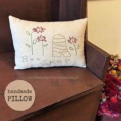 a pillow sitting on top of a wooden chair next to flowers and a potted plant