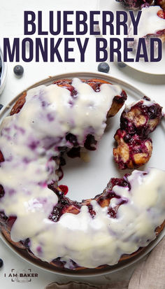 a blueberry monkey bread is on a plate with white icing and drizzled