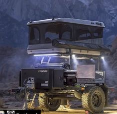 an off road vehicle with its lights on in the desert at night, near mountains