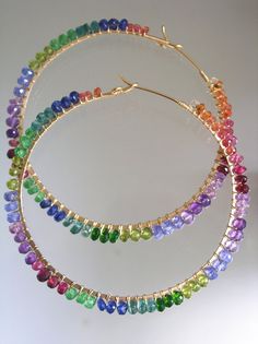 a pair of multicolored beaded hoop earrings on a white surface with gold plated ear wires