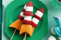 fruit skewers with marshmallows and strawberries arranged on a green plate