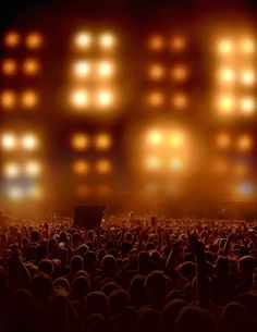 a large group of people standing in front of a stage with bright lights on it