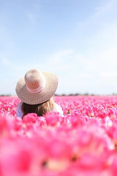 a woman wearing a hat in a field of pink flowers