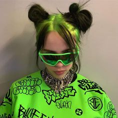 a woman with green hair and sunglasses on her head wearing a neon green shirt that has graffiti all over it