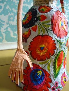 a vase with flowers painted on it and a hand holding the handle