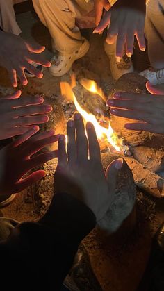 several hands reaching for something in the fire