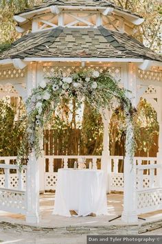 a white gazebo decorated with flowers and greenery