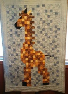 a quilted giraffe is hanging on the wall