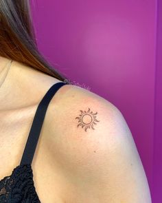 a woman with a small sun tattoo on her shoulder