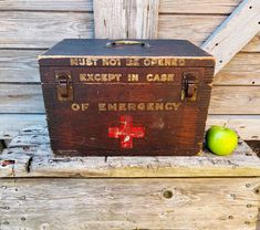 an old wooden chest sitting on top of a bench next to an apple and fence