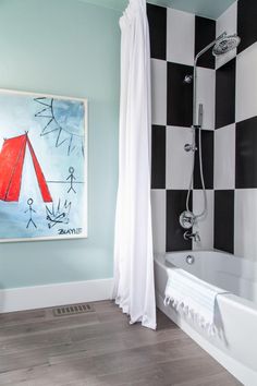 a bathroom with black and white checkered walls, a painting on the wall, and a bathtub