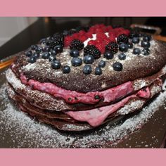 a chocolate cake topped with berries and powdered sugar