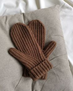 a knitted mitten laying on top of a pillow