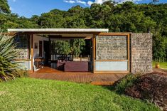 an outdoor living area with stone walls and wooden floors, surrounded by lush green trees