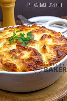 a close up of a casserole in a dish on a wooden table with utensils