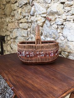 a wicker basket sitting on top of a wooden table next to a stone wall