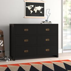 a black dresser sitting in a room next to a rug and a painting on the wall