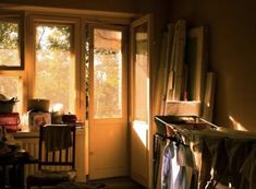 the sun shines through two windows into a room filled with furniture and other items