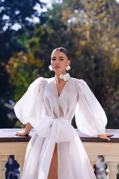 a woman in a white dress standing on a balcony