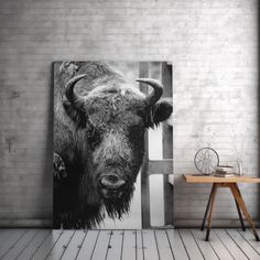 a black and white photo of a bison on a wall in a room with brick walls