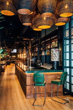 a bar with green chairs and lights hanging from the ceiling