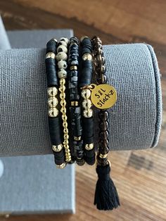 This 4mm black stack consists of 5 bracelets, perfect for everyday wear and every occasion.  *In this stack you will receive* * 2 Heishi bracelets with gold round beads and an S&L charm.   * Smokey quarts bead with 14k gold spacers and a black tassel.  * Natural stone bead in black and white with gold spacers.  * Dalmatian bead with gold accent.   All S&L Stackz come in a muslin bag for easy storage and gifting! If you need a special gift for that someone, these stacks are perfect!  Bracelets are made with quality stretchy elastic material. Heishi bracelets have double elastic.  >> Try rolling one bracelet at a time << >>Do not over stretch<< > Please keep in mind, this stack is made to order. FINAL SALE > Color & size of beads may vary due to supply.  > Follow instructions of care. Keep a Bracelets Heishi, Stacked Beaded Bracelets, Stack Bracelet, Bracelets Design, Rubber Bracelets, Gold Armband, Diy Bracelet Designs, Hematite Bracelet, Gold Bead Bracelets