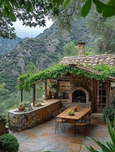 an outdoor kitchen and dining area with mountains in the backgroung, surrounded by greenery