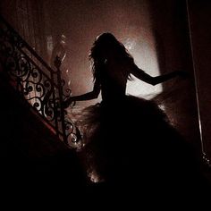 a woman is walking down the stairs in a dark room with her arms spread out